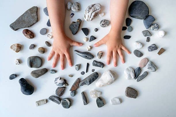Child hands with pebbles — sensory discovery